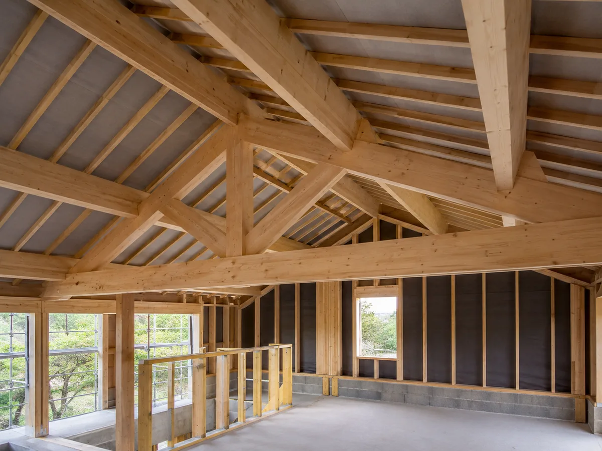 Charpente traditionnelle neuve en résineux, fermes et chevrons apparents sur une maison en construction