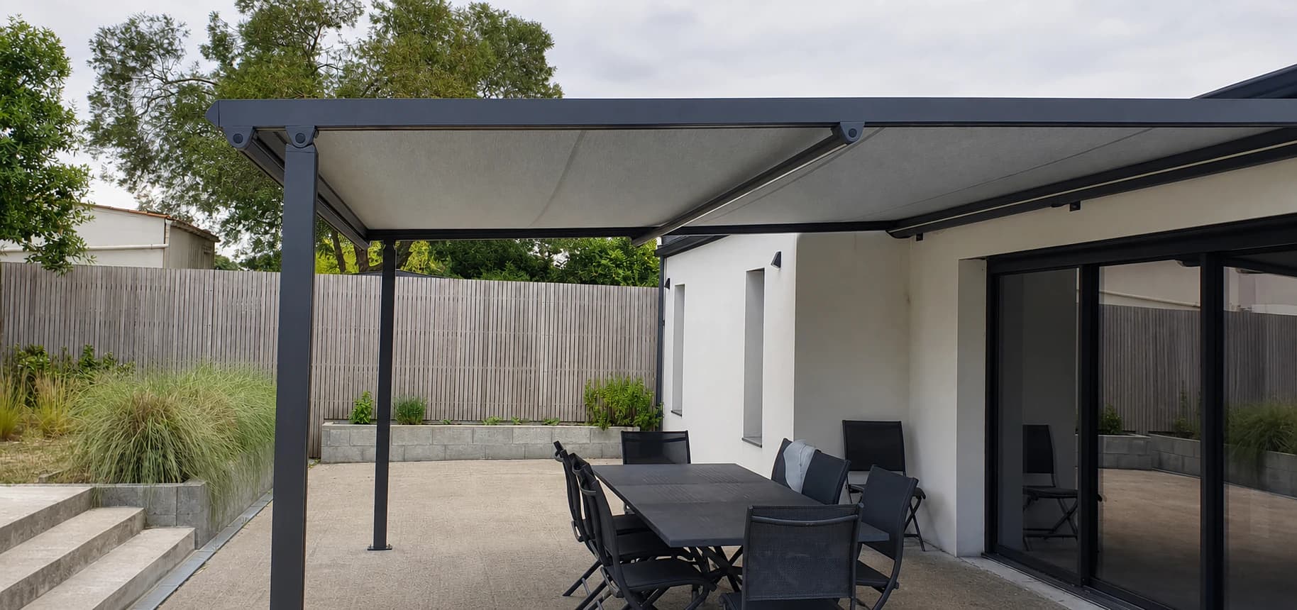 Pergola anthracite à toile déployée au-dessus d'une terrasse