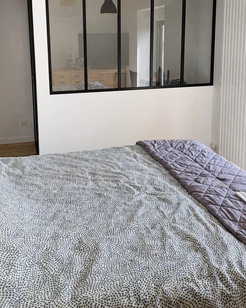 Verrière d'atelier noire séparant une chambre d'une pièce voisine